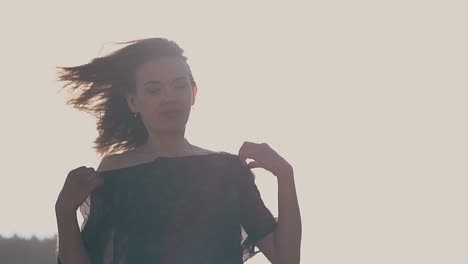 happy lady fixes sleeves of dress against sky slow motion