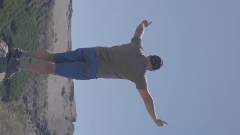 a man standing at a mountain peak with arms raised in a gesture of achievement, success and freedom