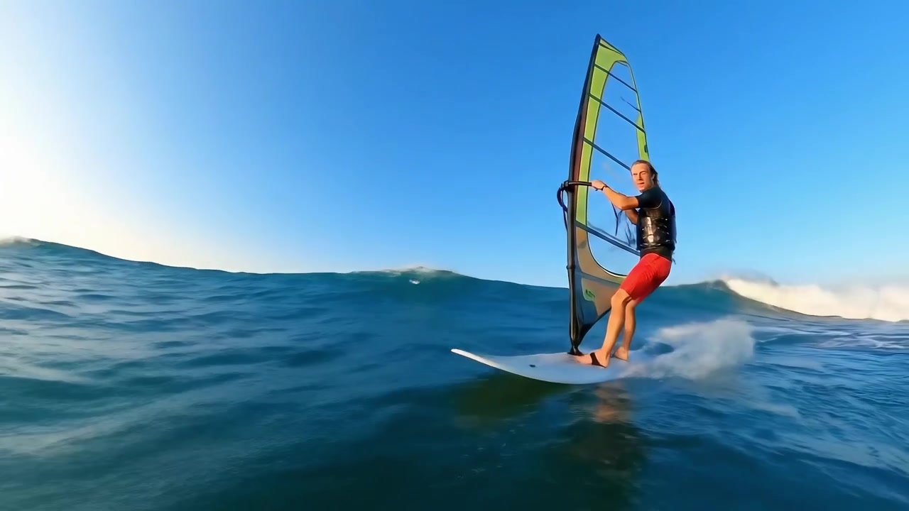 Hombre haciendo windsurf sobre las olas del océano bajo un cielo azul claro