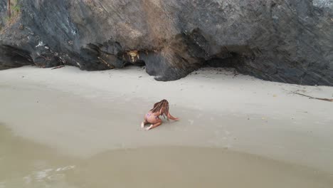 Una-Chica-En-Bikini-Divirtiéndose-En-La-Playa-Con-Acantilados-Rocosos-Al-Fondo