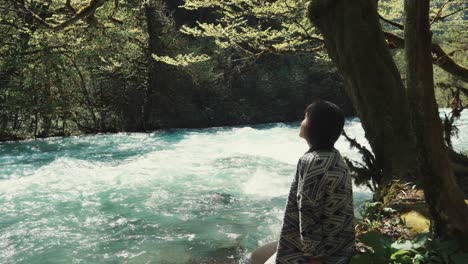 woman relaxing by a river in a forest