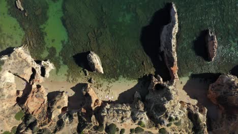 Amazing-Birdseye-drone-topdown-shot-of-a-private-secret-beach-surrounded-by-ocean-cliffs-and-green-clear-water