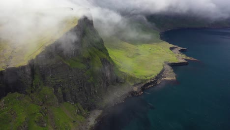 Clouds-rolling-over-coastal-cliffs-in-remote-Faroe-Islands,-aerial-forward-dolly