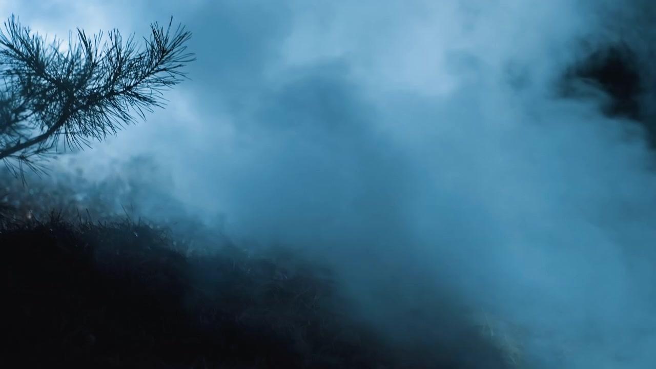 Niebla azul que se extiende y asciende por la ladera de una colina de noche, suavizando el terreno cubierto de hierba y ocultando parcialmente la silueta de los arbustos, mientras una bruma en capas se desplaza por el primer plano con una atmósfera inquietante y baja visibilidad.