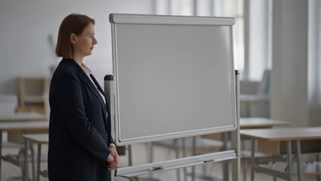 teacher standing next to an empty whiteboard in a classroom