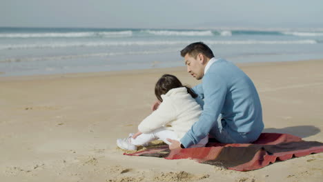 Japanischer-Vater-Und-Süße-Kleine-Tochter-Sitzen-Auf-Decke-Am-Strand