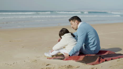 해변에서 담요에 앉아 일본 아빠와 귀여운 작은 딸