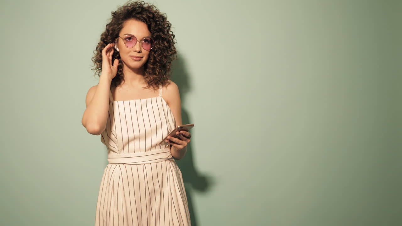 Donna con capelli ricci in una tuta a righe che usa lo smartphone