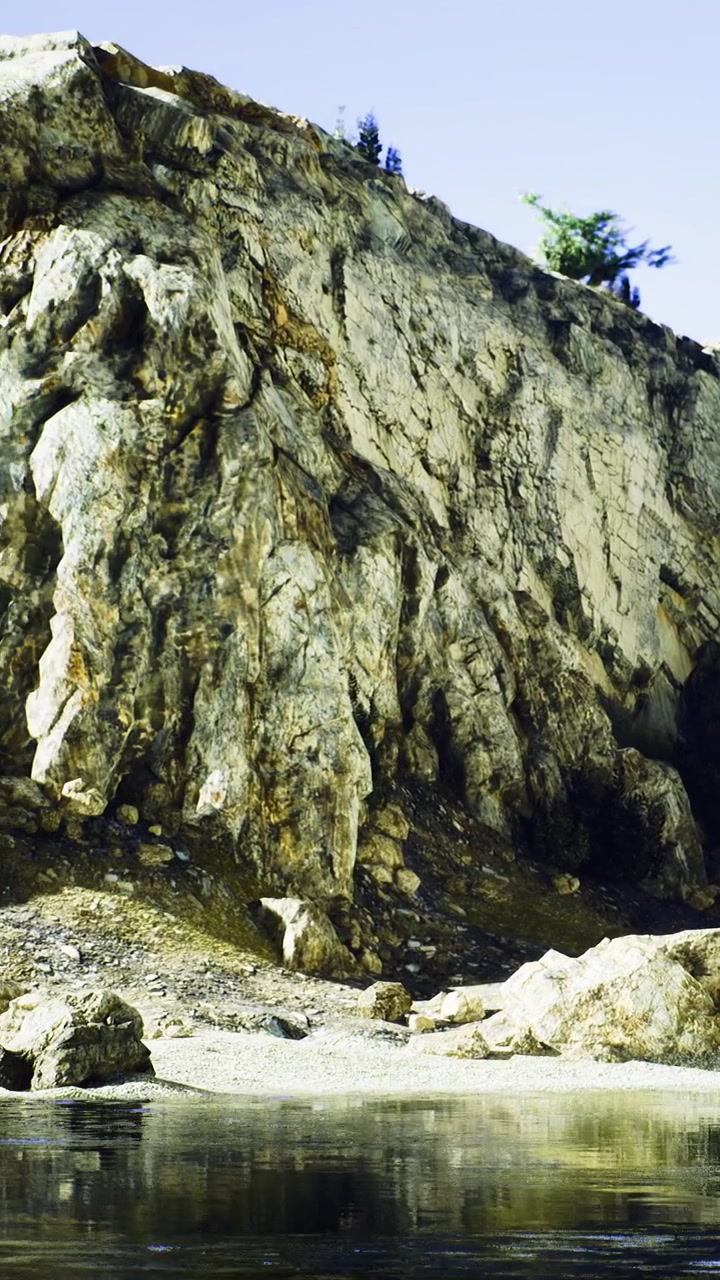 Scogliera rocciosa vicino ad acqua calma con alberi sotto un cielo sereno di giorno.