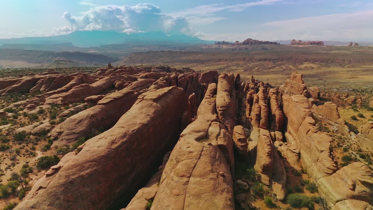 Long rocky apexes of Arches National Park in Utah, USA. Beautiful sunny landscape. Cloudscape over the mount at backdrop.