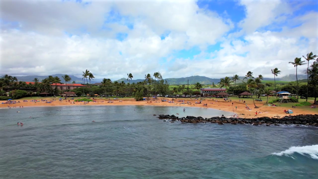 Riprese drone 4K della spiaggia di Poipu che mostrano una giornata rilassante in spiaggia mentre le persone fanno snorkeling e giocano nella sabbia