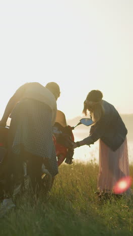 두 명의 여성이 배경에 흐릿한 물체 근처의 넓은 열린 잔디에서 빨간색 전력 자전거를 조심스럽게 청소하고 있습니다.