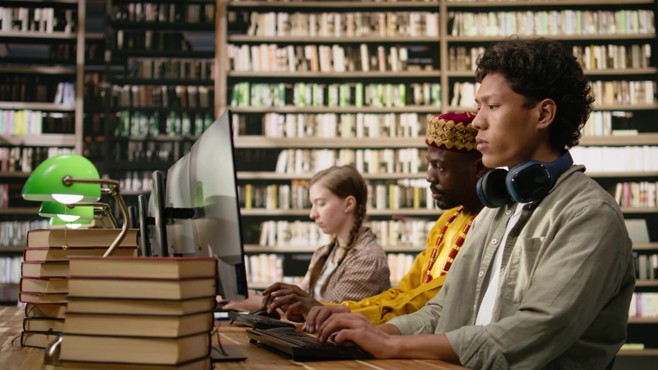 Student with headphones around his neck typing at desktop computer