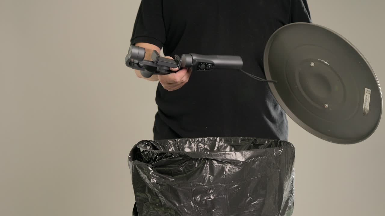 A man is throwing an old unnecessary gimbal into the trash bin