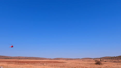 red chopper used for game census comes in for landing in dry african landscape