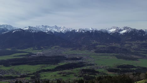 Drone fly above Forest with Snow Covered Mountain Summits in Background
