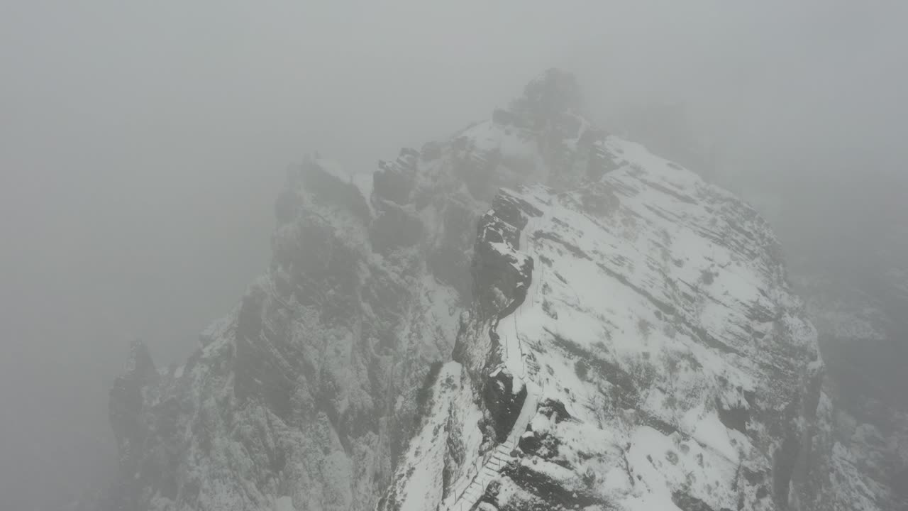 Drone shot aboce the ridge of Ninho da Manta in Madeira during a snowstorm with a moody, dark and suspense feeling