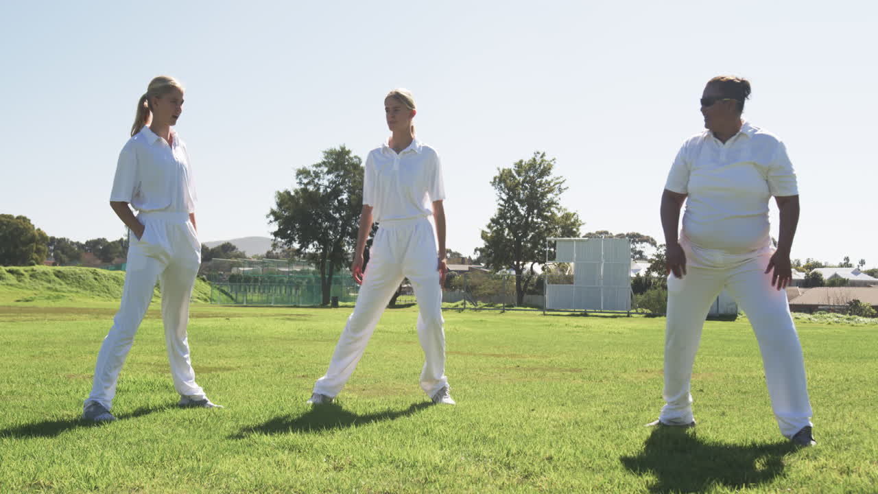 Stretching arms, female cricket players warming up on field before game