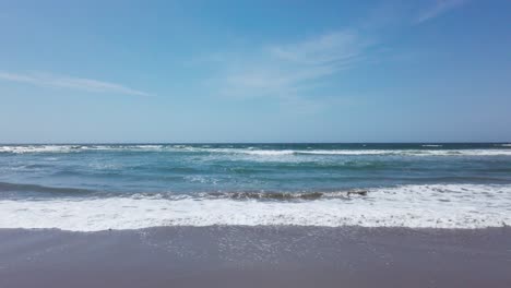 Blue-ocean-waves-on-the-sandy-beach-and-clear-blue-sky