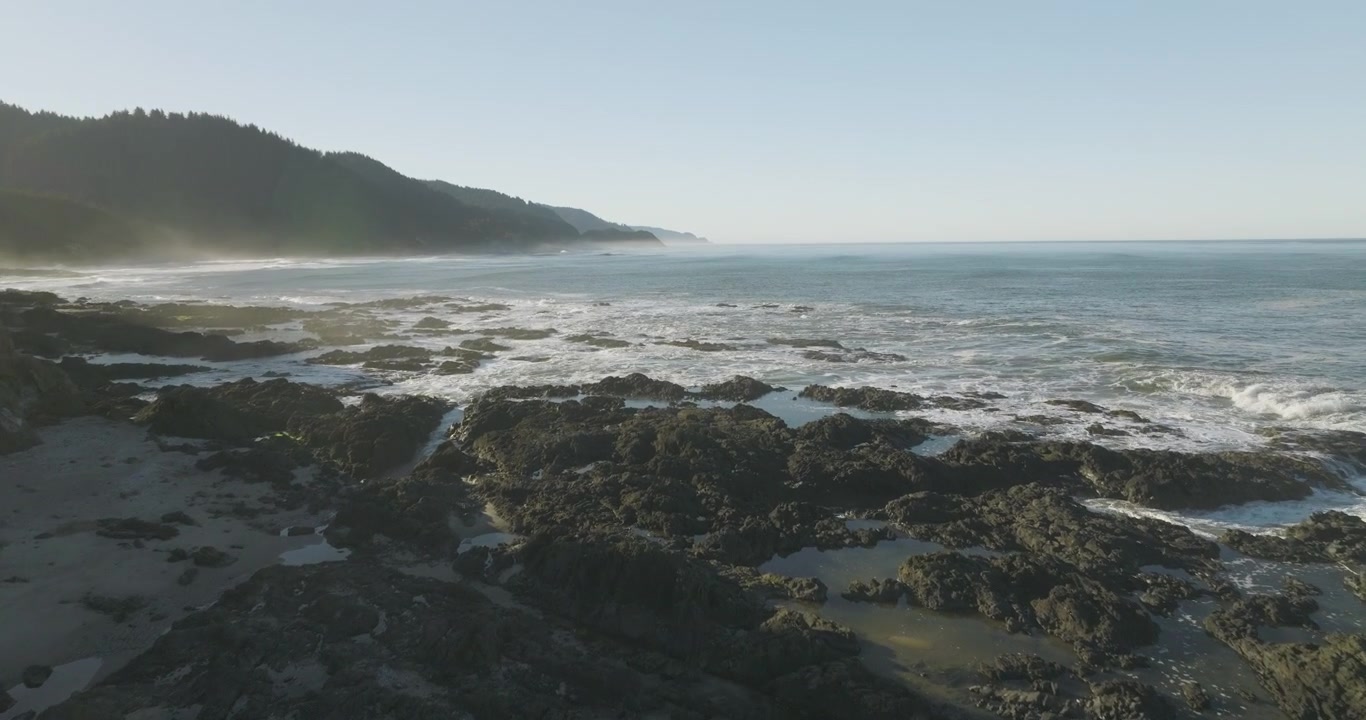 Aerial dolly between the rugged coastline at Cape Perpetua, Oregon Coast, with waves crashing into the rocky shore