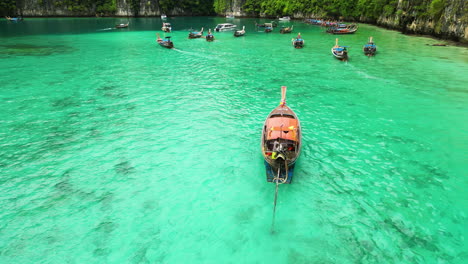 embarcación de agua de cola larga de madera que navega en aguas tailandesas turquesas frente a la isla de phi phi