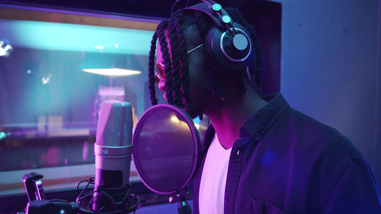 hombre afroamericano grabando una canción en un estudio con una productora