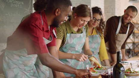 mujer alegre preparando ensalada durante la clase magistral de cocina