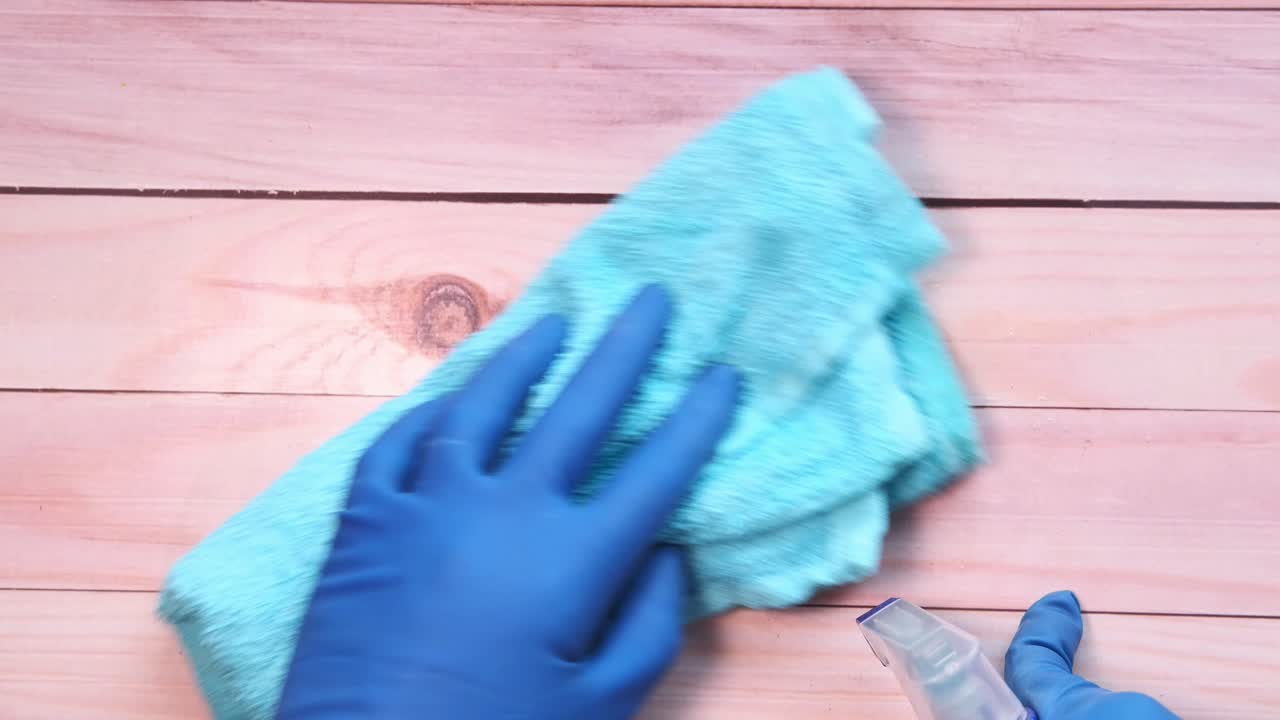 limpieza de una superficie de madera con un paño y una botella de pulverización