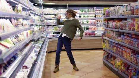 Full-length-footage-of-young-woman-dancing-through-grocery-store-aisles.-Excited-woman-having-fun,-dancing-supermarket.-Slow