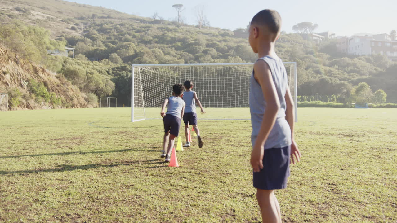 Playing soccer, kids practicing drills with cones on school field