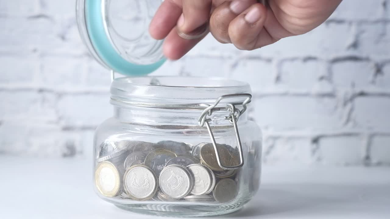 ahorrar dinero: poner monedas en un frasco de vidrio