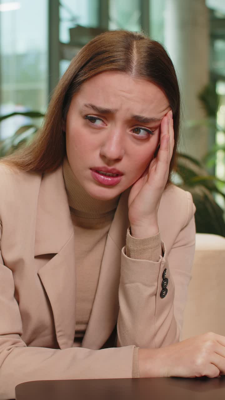 Depressed desperate young businesswoman feeling worried about financial problems in office lobby