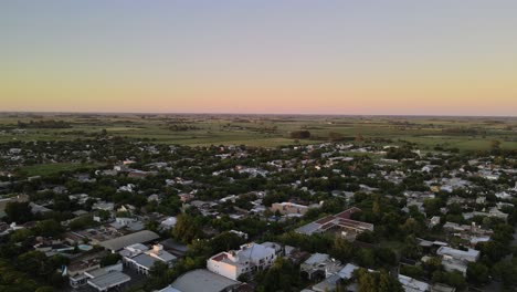 dolly out flying over santa elisa countryside town houses surrounded by trees and farmlands in background, entre rios, argentina