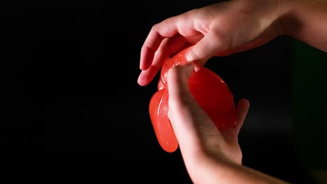 hands stretching and squeezing red slime