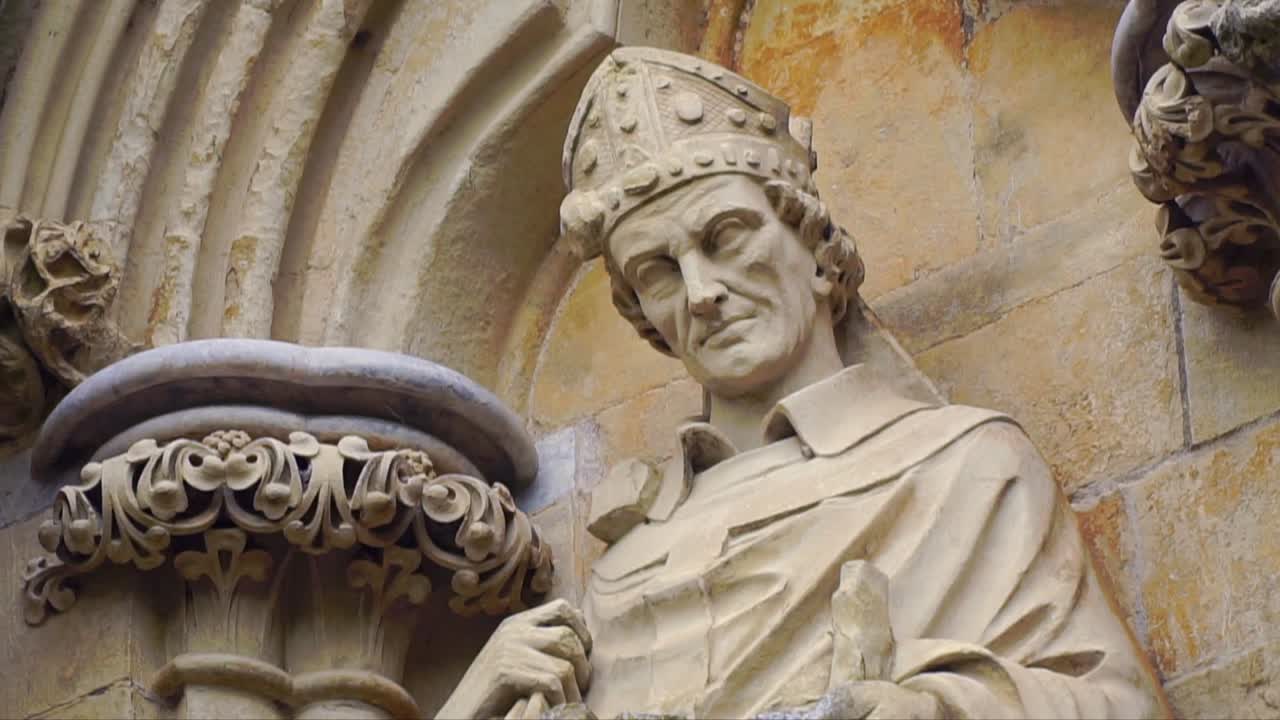 Detailed stone sculpture of a bishop with mitre hat on the exterior wall of Salisbury Cathedral, showcasing Gothic craftsmanship in historic English architecture.
