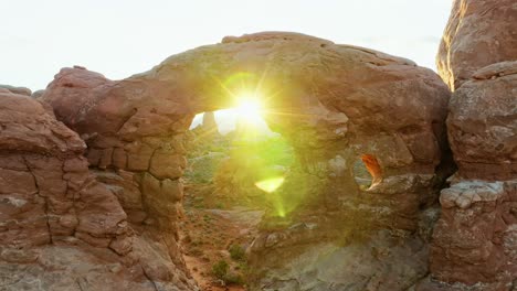sol brillante brillando a través del agujero del doble arco en arches natural park, utah, estados unidos