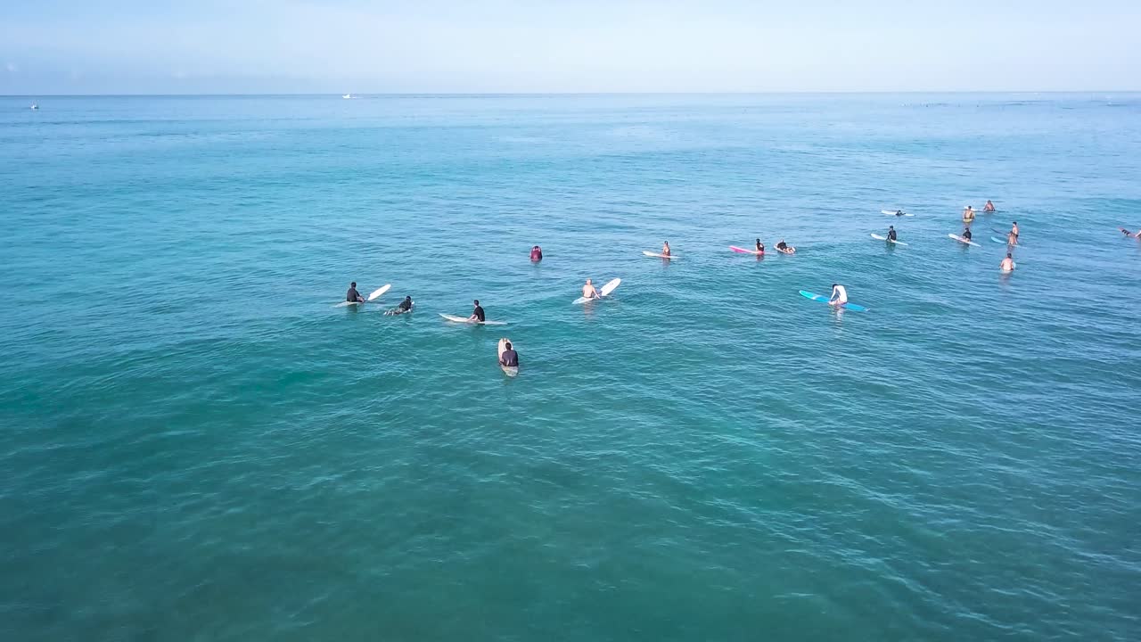 muchos surfistas esperando una ola en la playa de waikiki honolulu hawaii en un día de cielo azul brillante, antena estática