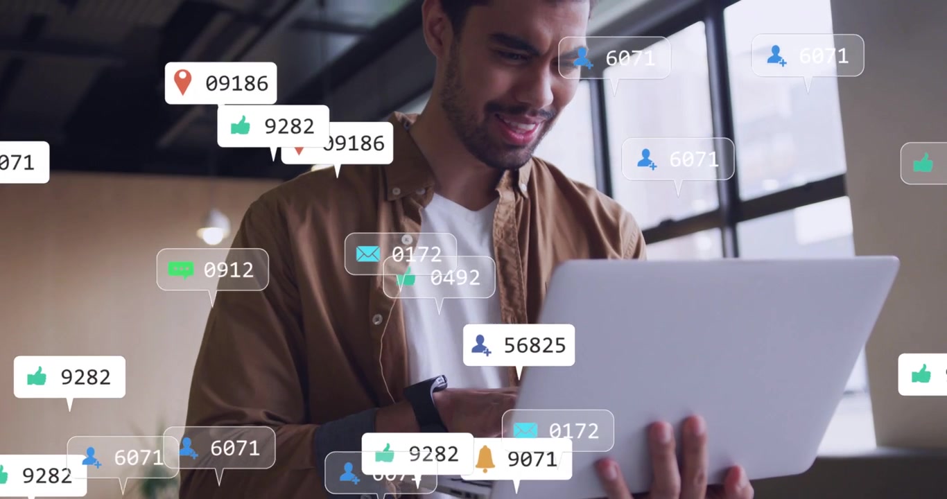 Male holding laptop typing while notification bubbles appearing and multiplying, causing soft smile