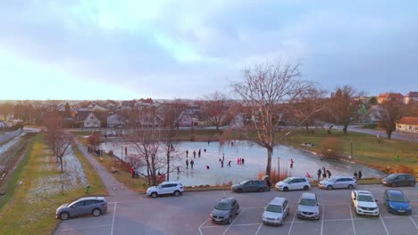 scenic frozen lake with people ice skating in winter - drone shot