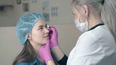 brow-master-applies-paint-on-woman-face-in-beauty-clinic