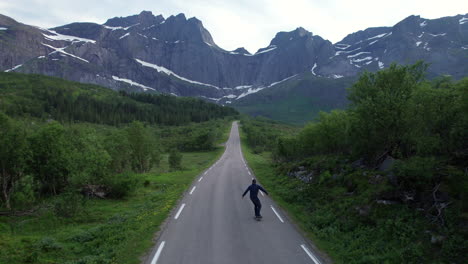 skater enjoying the scenic view on a empty road in lofoten during midnight sun in norway, forwarding shot