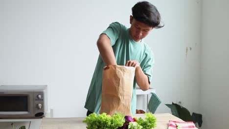 young man unpacking fresh groceries in kitchen