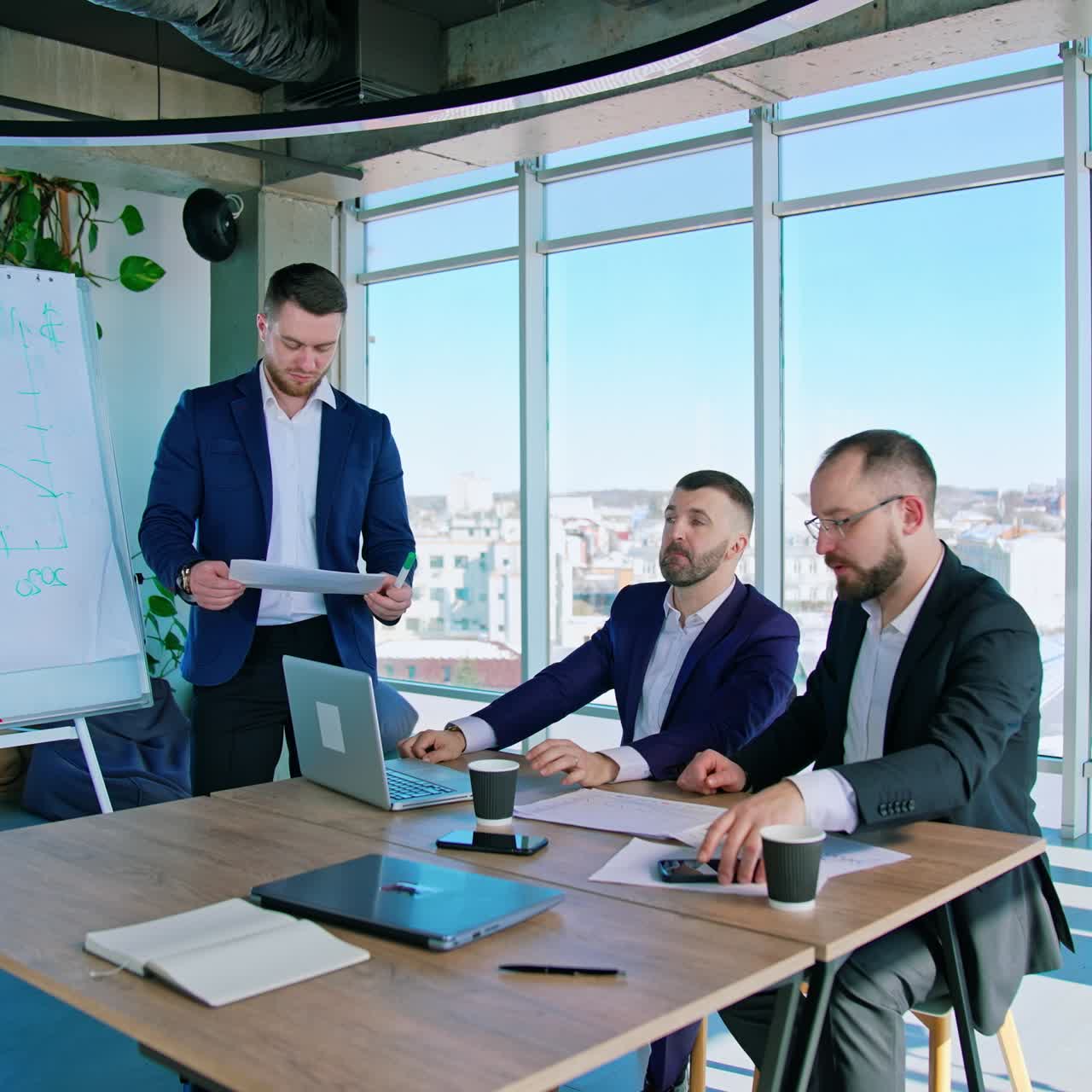 Teamwork of businessmen. Group of successful entrepreneurs talking in office room on the background of city with window view