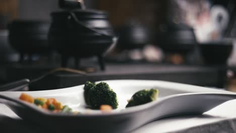 Plato-Vacío-De-Verduras-En-Cámara-Lenta-Con-Algunas-Ollas-En-Una-Mesa-Ocupada-Cocinando