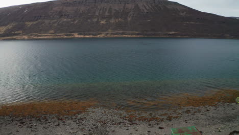 drone vuela sobre un hombre nadando en una piscina geotérmica en westfjords, oeste de islandia - antena