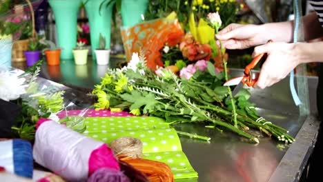 florista femenina recortando el tallo de la flor en la tienda de flores