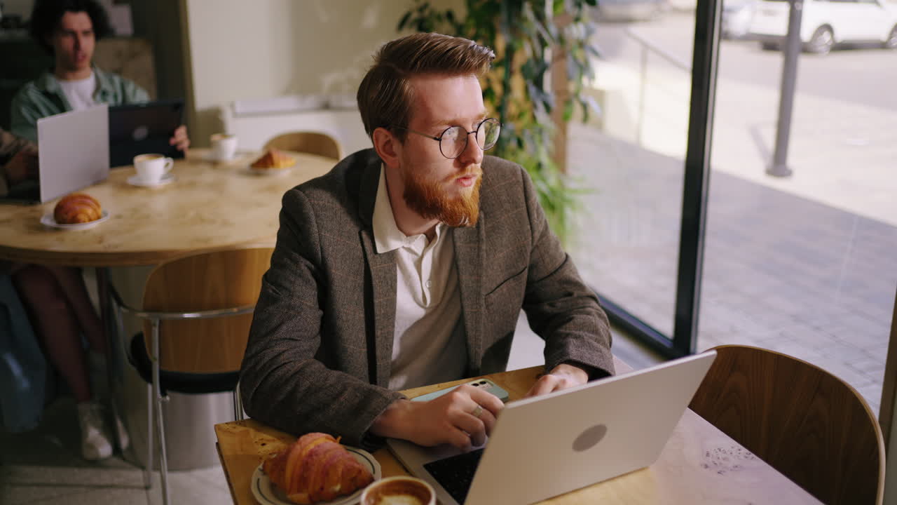 Uomo che lavora al computer portatile in un caffè