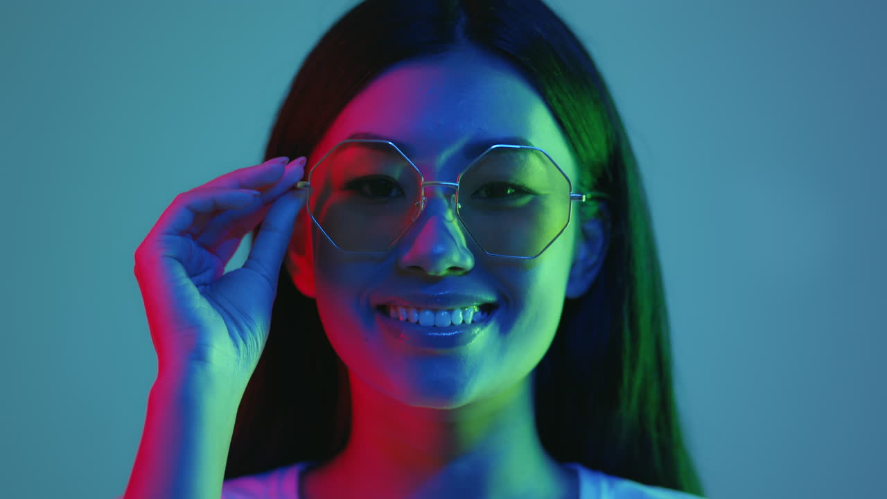 Happy Woman Wearing Stylish Sunglasses Under Neon Light