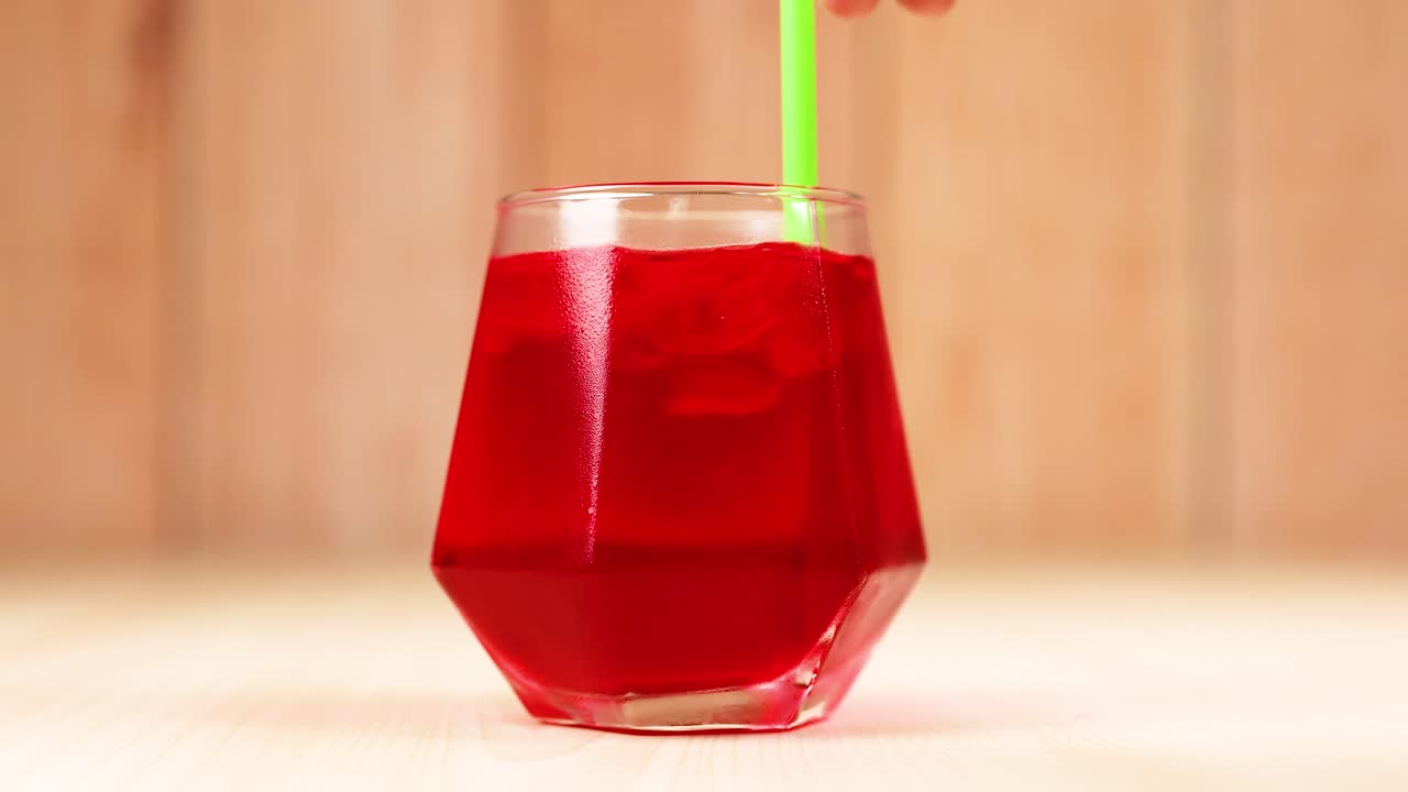 Hand stirring drink with a green straw