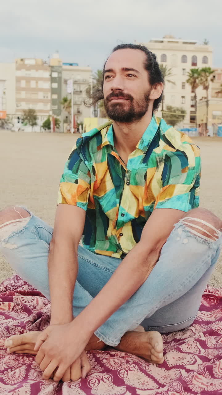Hombre sentado en la playa con camisa estampada